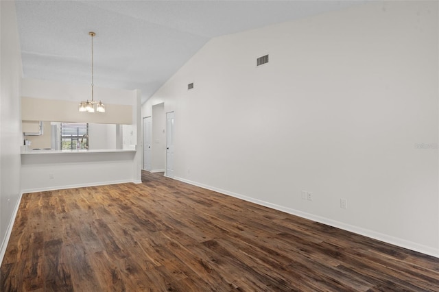 empty room with vaulted ceiling, a chandelier, and wood-type flooring