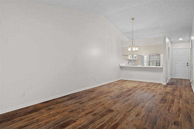 unfurnished living room with vaulted ceiling, dark hardwood / wood-style floors, and a notable chandelier