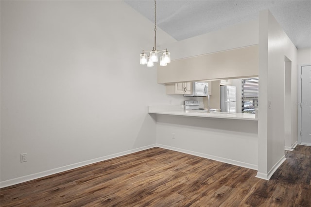 unfurnished dining area featuring lofted ceiling, a chandelier, dark wood-type flooring, and a textured ceiling