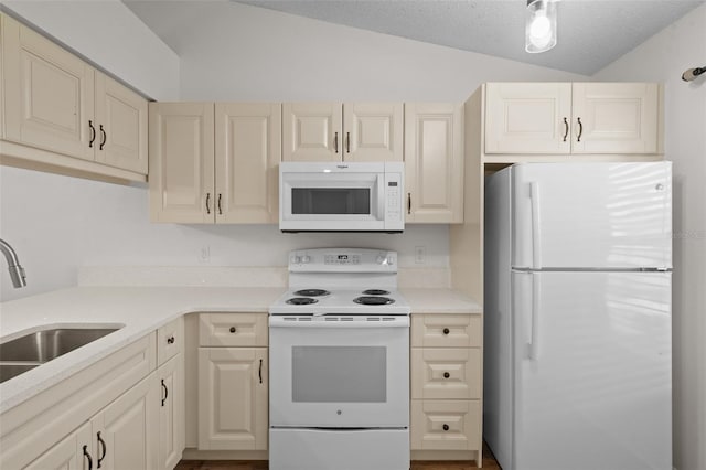 kitchen with lofted ceiling, sink, white appliances, a textured ceiling, and cream cabinetry