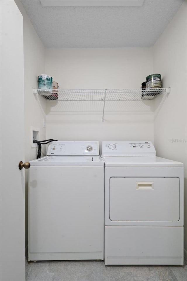 washroom with a textured ceiling and washer and clothes dryer