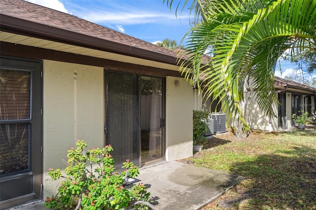 view of exterior entry featuring central AC and a yard