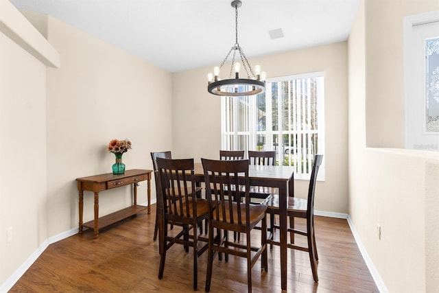 dining space featuring dark hardwood / wood-style floors and an inviting chandelier