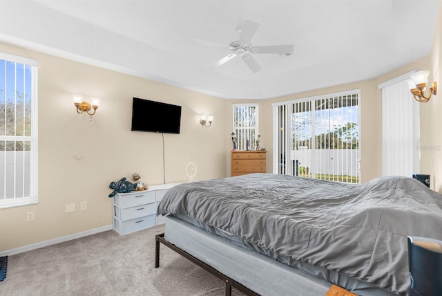 bedroom with light carpet, access to outside, a raised ceiling, and ceiling fan