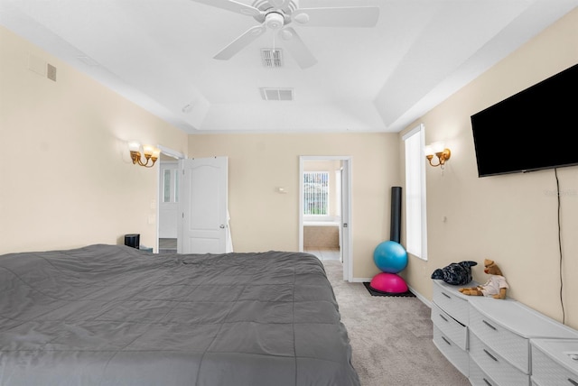 bedroom with ceiling fan, light colored carpet, and a tray ceiling