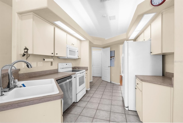 kitchen featuring sink, light tile patterned floors, a tray ceiling, white appliances, and white cabinets