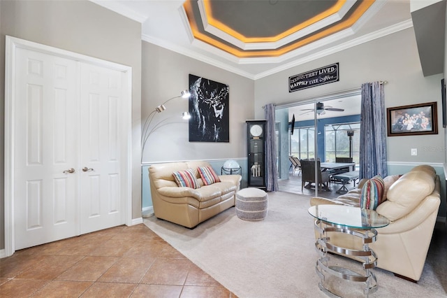 living room featuring a tray ceiling, tile patterned floors, ornamental molding, and ceiling fan