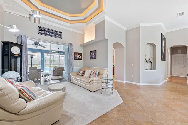 living room with a tray ceiling, ceiling fan, ornamental molding, and light tile patterned flooring