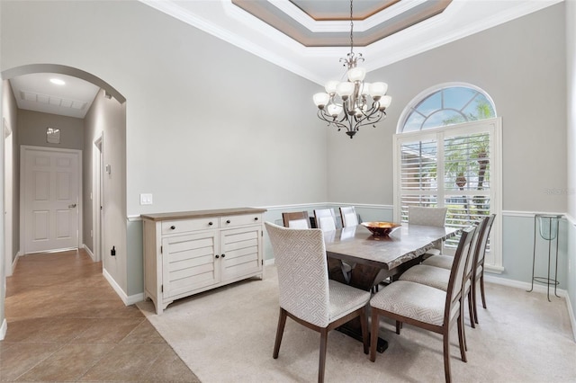 tiled dining area with an inviting chandelier, a tray ceiling, and ornamental molding