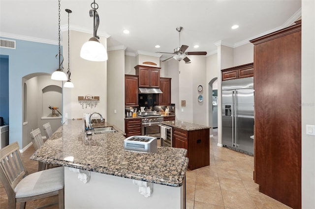 kitchen featuring kitchen peninsula, hanging light fixtures, high quality appliances, sink, and a breakfast bar