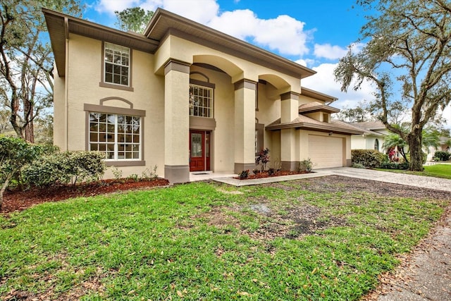 mediterranean / spanish-style house with a garage, a front yard, concrete driveway, and stucco siding