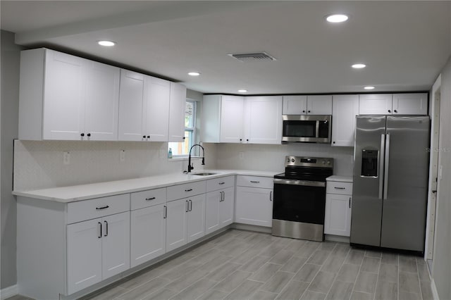 8703 Robilina Rd, Port Richey, FL 34668 - kitchen with sink, backsplash, white cabinetry, and appliances with stainless steel finishes
