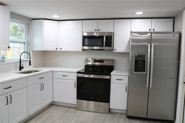 8703 Robilina Rd, Port Richey, FL 34668 - kitchen with decorative backsplash, sink, white cabinetry, and stainless steel appliances