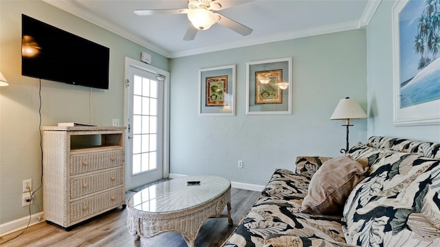 living room featuring light wood-type flooring, ceiling fan, and ornamental molding