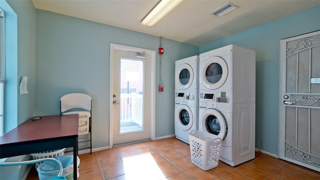 clothes washing area with light tile patterned floors and stacked washer / dryer