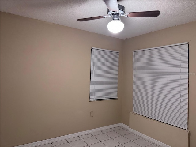 tiled empty room with ceiling fan and a textured ceiling