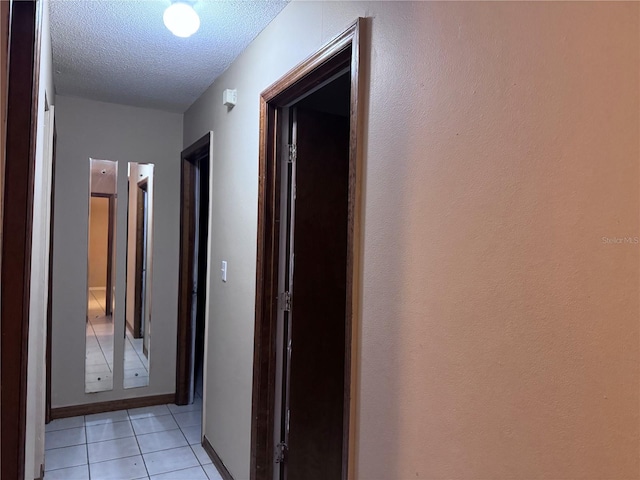 hall featuring a textured ceiling and light tile patterned flooring