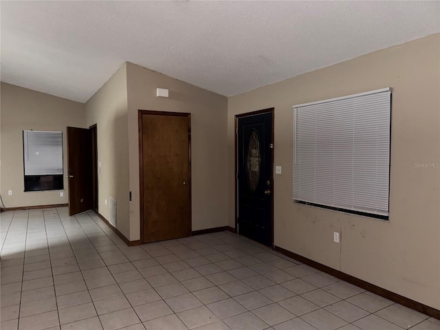 tiled empty room with a textured ceiling and lofted ceiling