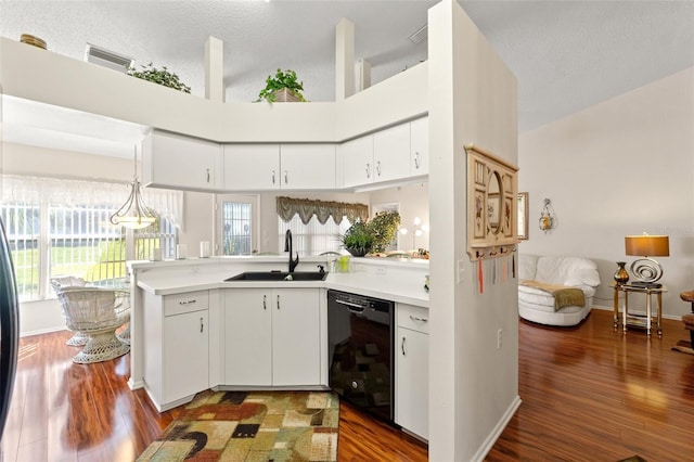 kitchen featuring decorative light fixtures, kitchen peninsula, sink, a high ceiling, and black dishwasher