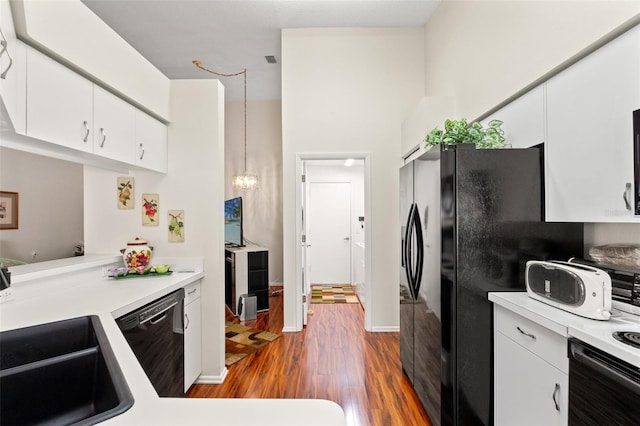 kitchen featuring black appliances, hanging light fixtures, white cabinetry, and hardwood / wood-style flooring