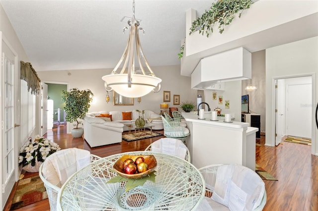 dining space featuring a textured ceiling, lofted ceiling, and wood-type flooring