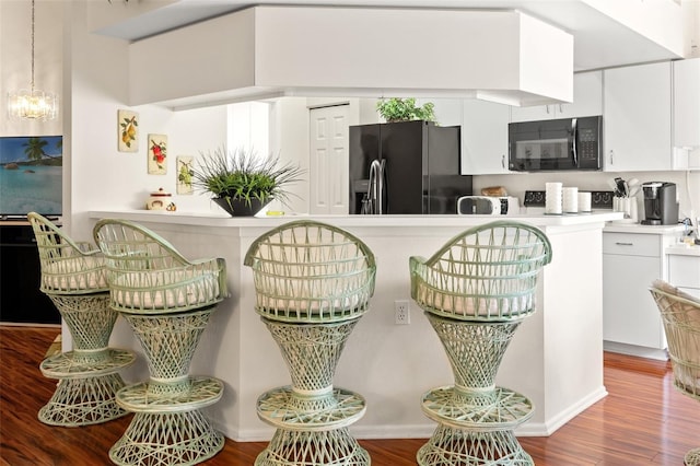 kitchen with an inviting chandelier, hardwood / wood-style floors, white cabinets, and black appliances