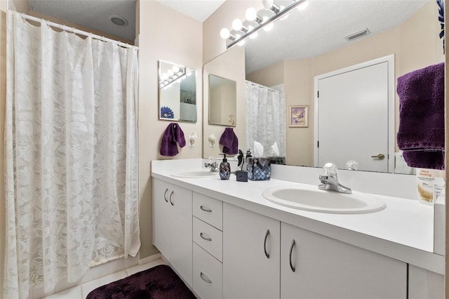 bathroom with a textured ceiling, tile patterned floors, and vanity