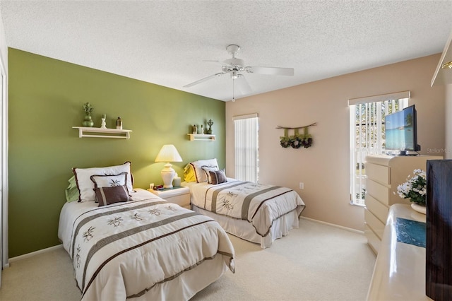 bedroom with ceiling fan, light carpet, and a textured ceiling