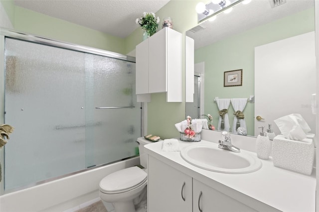 full bathroom featuring a textured ceiling, shower / bath combination with glass door, vanity, and toilet