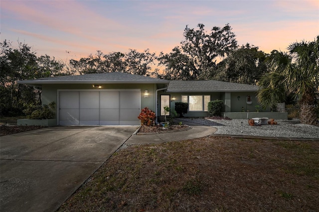 view of front of property with stucco siding, an attached garage, roof with shingles, and driveway