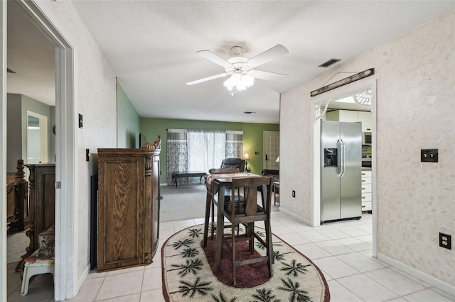 dining area featuring a textured ceiling, ceiling fan, and light tile patterned floors