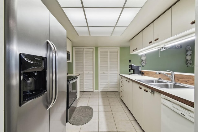 kitchen with light tile patterned floors, stainless steel appliances, white cabinetry, and sink