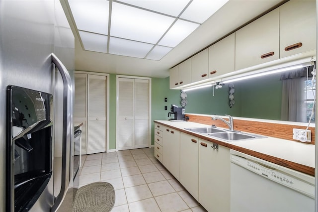 kitchen with white cabinets, stainless steel refrigerator with ice dispenser, sink, light tile patterned flooring, and white dishwasher