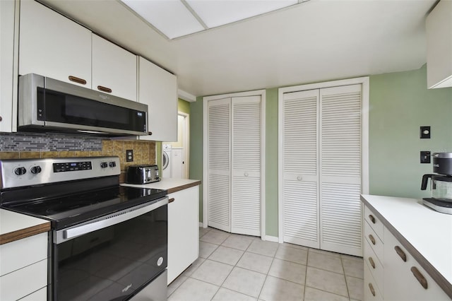 kitchen featuring white cabinets, decorative backsplash, light tile patterned floors, and stainless steel appliances