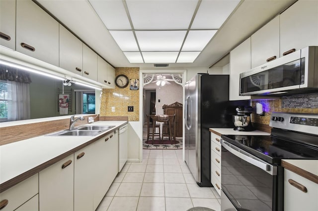 kitchen featuring backsplash, sink, white cabinetry, appliances with stainless steel finishes, and light tile patterned floors