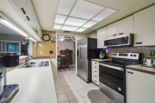 kitchen featuring backsplash, sink, white cabinetry, stainless steel appliances, and light tile patterned floors