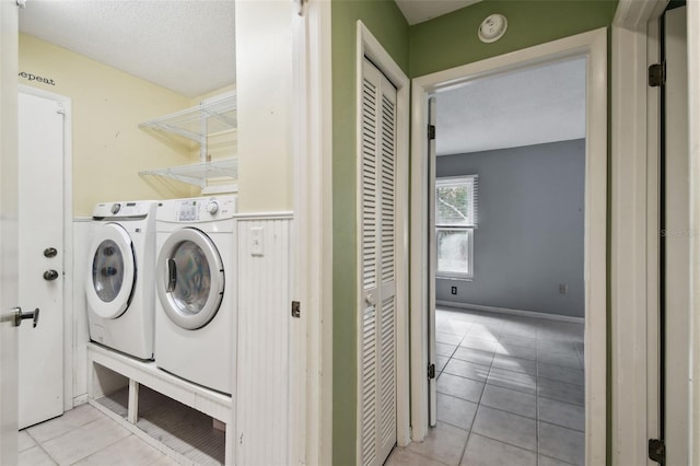 laundry room with a textured ceiling, separate washer and dryer, and light tile patterned floors