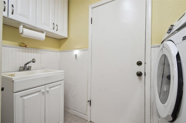 laundry room with wood walls, sink, washer / dryer, and cabinets