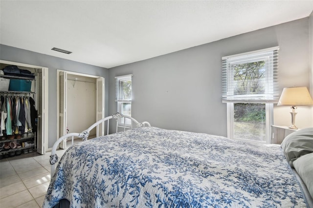 bedroom featuring light tile patterned floors and two closets