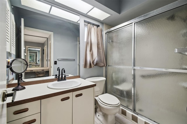 bathroom featuring toilet, a shower with door, and vanity