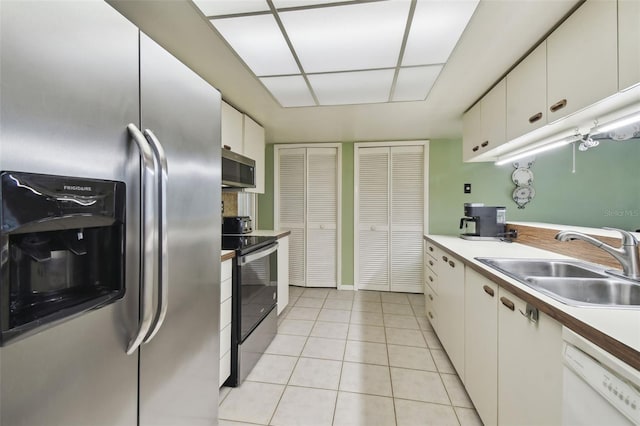 kitchen with light tile patterned floors, sink, white cabinetry, and appliances with stainless steel finishes