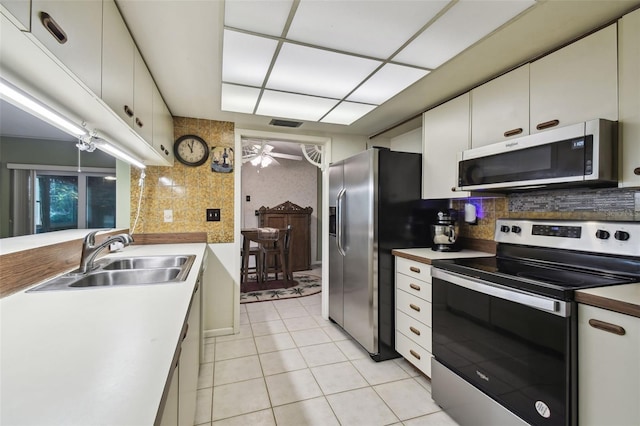 kitchen with appliances with stainless steel finishes, white cabinets, backsplash, and sink