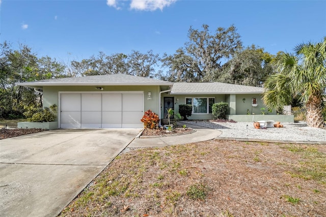 ranch-style house with a shingled roof, concrete driveway, an attached garage, and stucco siding