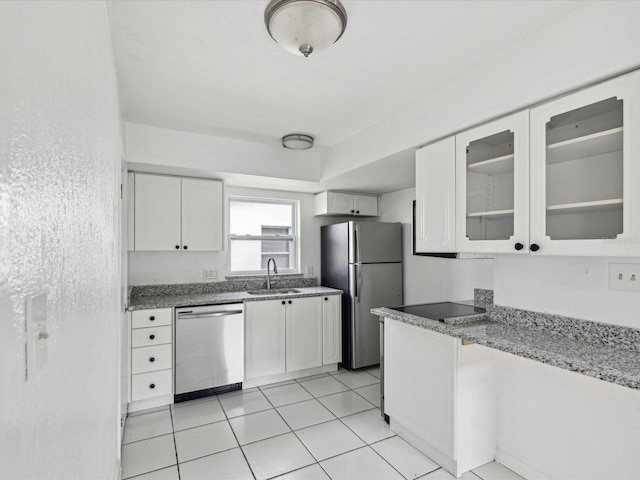 kitchen with sink, white cabinetry, appliances with stainless steel finishes, light tile patterned floors, and light stone counters