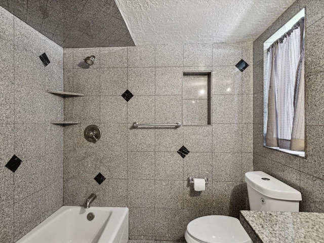 full bathroom with toilet, tiled shower / bath combo, tile walls, a textured ceiling, and vanity