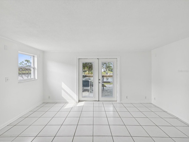 tiled empty room with a water view and french doors