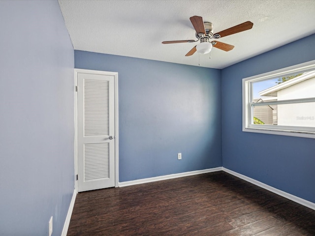 spare room with a textured ceiling, ceiling fan, and dark hardwood / wood-style floors