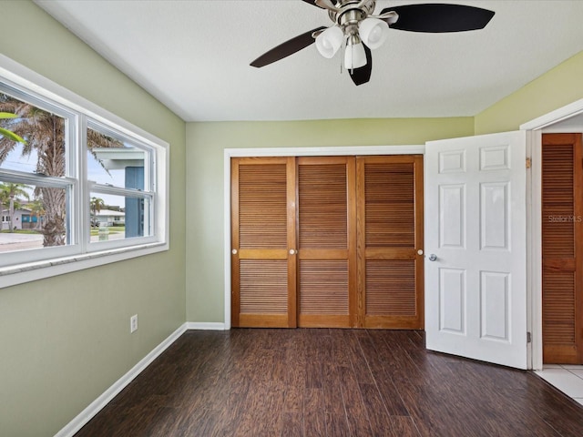 unfurnished bedroom with ceiling fan, dark wood-type flooring, and a closet