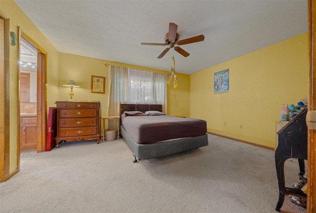 carpeted bedroom with ensuite bathroom and ceiling fan