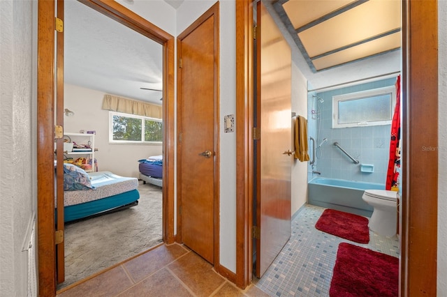 bathroom with tiled shower / bath, tile patterned floors, and toilet